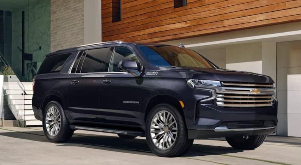 A black 2023 Chevy Suburban is shown parked on a driveway.