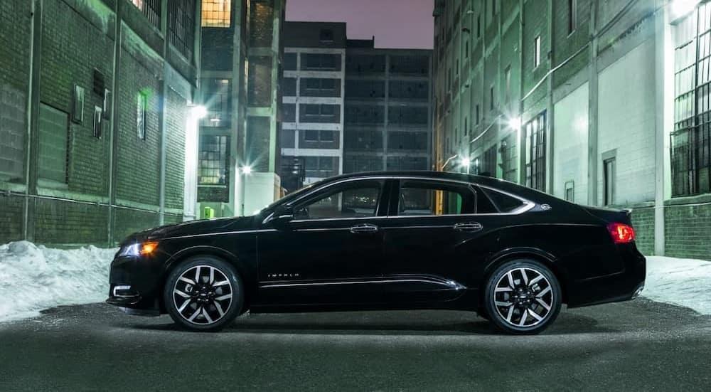 A black 2018 Chevrolet Impala Midnight Edition is shown parked near several buildings.