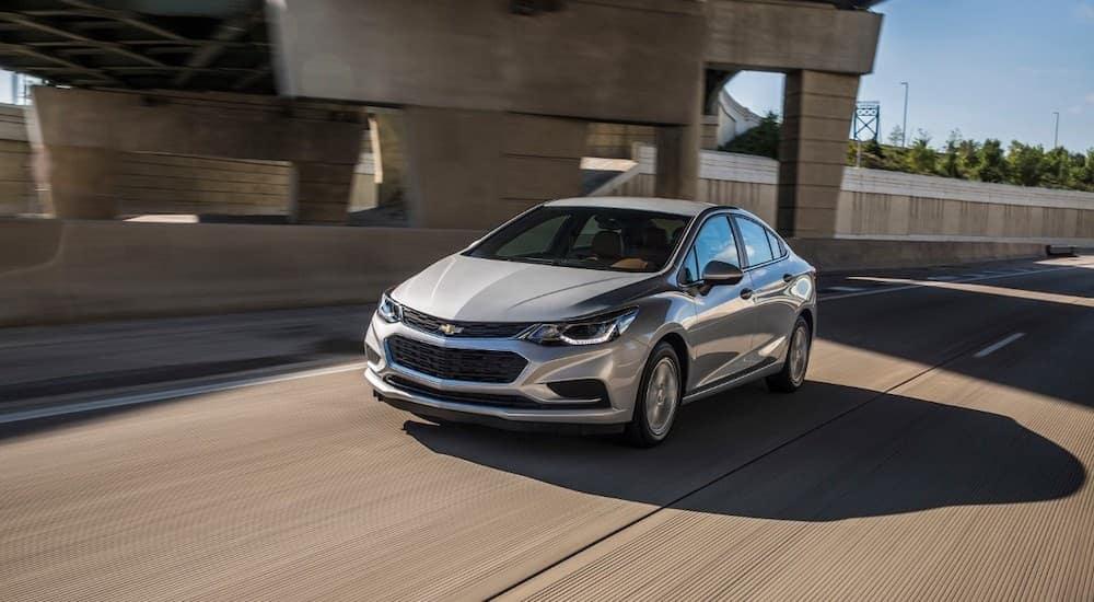 A silver 2017 Chevy Cruze is shown driving under an overpass.